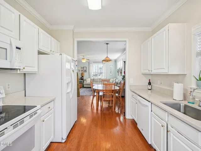 a kitchen with granite countertop a refrigerator a stove a sink a dining table and chairs with wooden floor