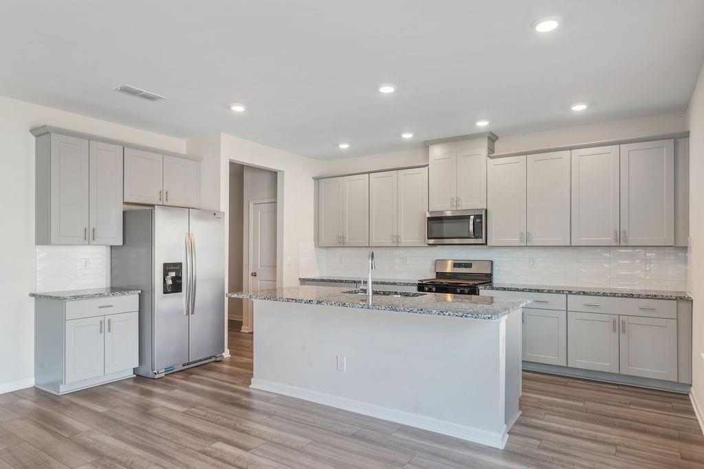 6901 Durham Lane Fairburn, GA 30213 - Photo 5 of 28 a kitchen with stainless steel appliances granite countertop a stove a sink a refrigerator and white cabinets with wooden floor