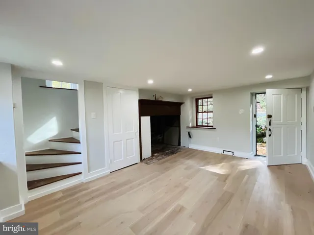 a view of an empty room with wooden floor and a fireplace