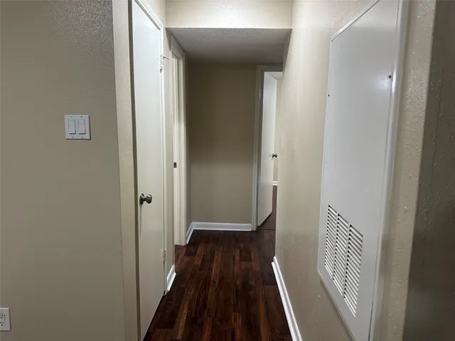 a view of a hallway with wooden floor and a bathroom