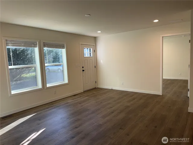an empty room with wooden floor and windows