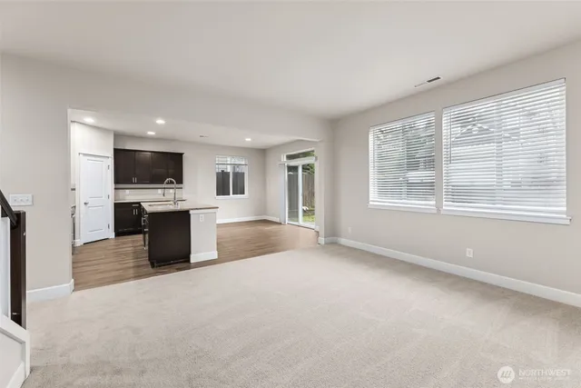 a view of kitchen with stainless steel appliances granite countertop a stove top oven a sink dishwasher a refrigerator and white cabinets with wooden floor