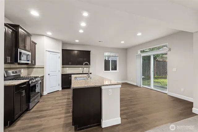 a large kitchen with stainless steel appliances kitchen island granite countertop a large counter top and wooden floors