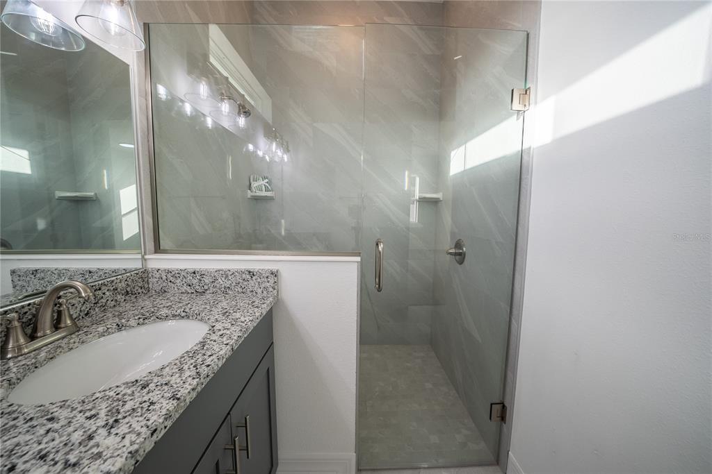 4720 Southeast 25th Street Ocala, FL 34480 - Photo 14 of 27 a bathroom with a granite countertop sink a mirror and shower