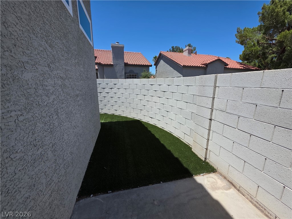 2275 Ramsgate Drive Henderson, NV 89074 - Photo 6 of 84 A private side yard with artificial turf, bordered by a textured stucco wall and block fencing, offers a serene outdoor retreat.