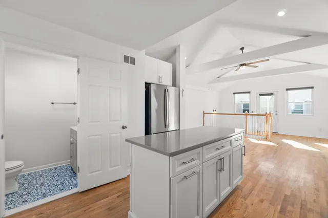 a kitchen with kitchen island a counter top space a sink a refrigerator and a window