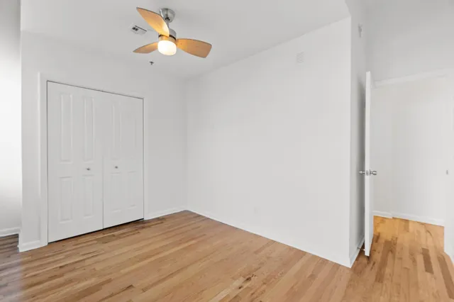 a view of an empty room with wooden floor and windows
