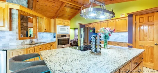 a kitchen with stainless steel appliances granite countertop a sink a counter top space and living room view