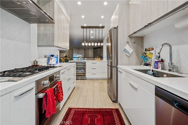 a kitchen with kitchen island stainless steel appliances a stove refrigerator sink and cabinets