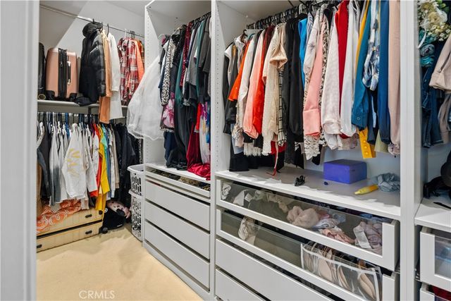 a view of walk in closet with clothes and shoes