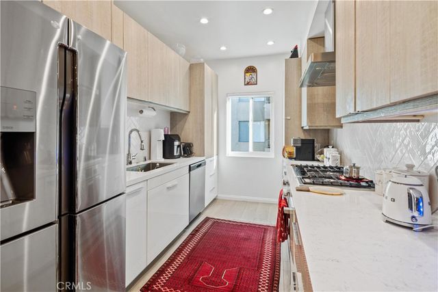 a kitchen with refrigerator a sink and wooden floor