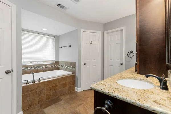 a bathroom with a granite countertop tub sink and mirror