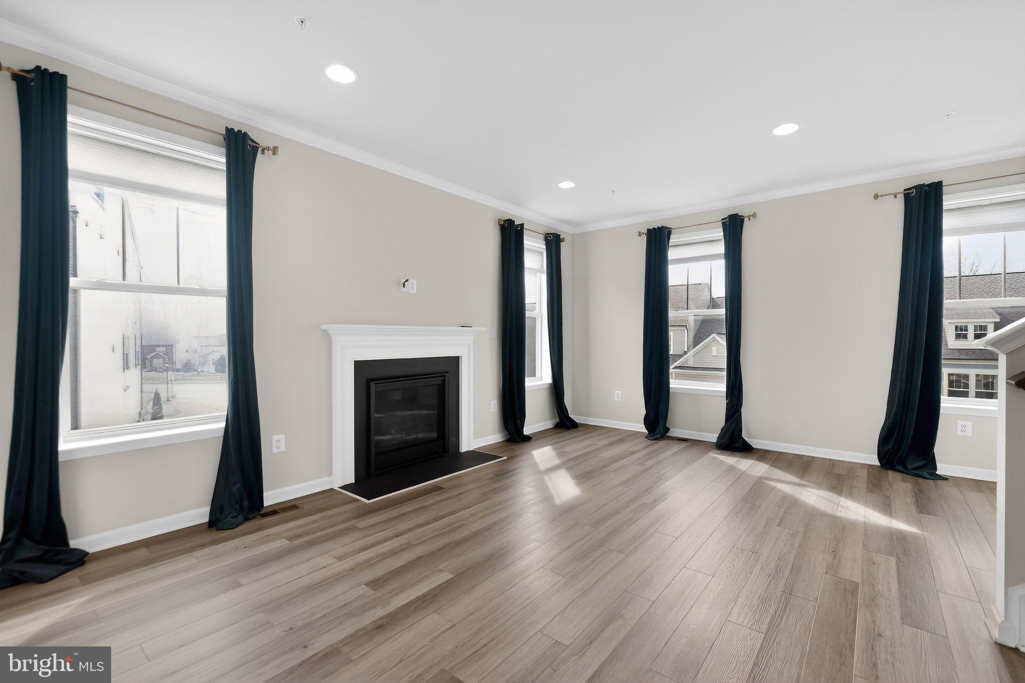 1518 Ricketts Road Frederick, MD 21702 - Photo 12 of 32 an empty room with wooden floor fireplace and windows