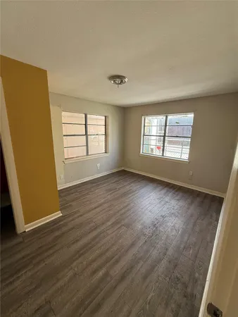 an empty room with wooden floor and window