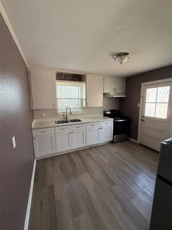 a large kitchen with cabinets wooden floor and stainless steel appliances