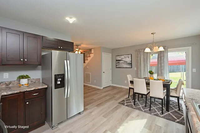 a kitchen with stainless steel appliances granite countertop a refrigerator a sink dishwasher a kitchen island with wooden floor and cabinets