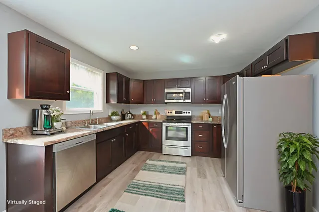 a kitchen with stainless steel appliances granite countertop a refrigerator a sink dishwasher a stove with wooden cabinets and floor