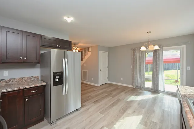 a view of a livingroom with a chandelier wooden floor and windows