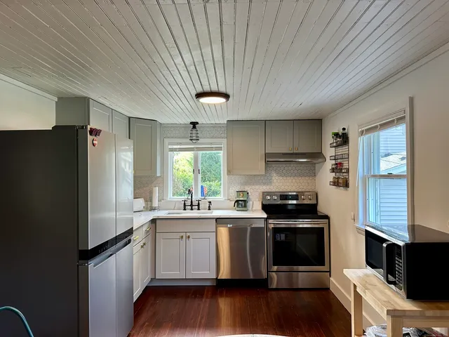 a kitchen with stainless steel appliances a sink a stove a refrigerator cabinets and wooden floor