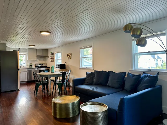 a living room with furniture and a dining table with wooden floor