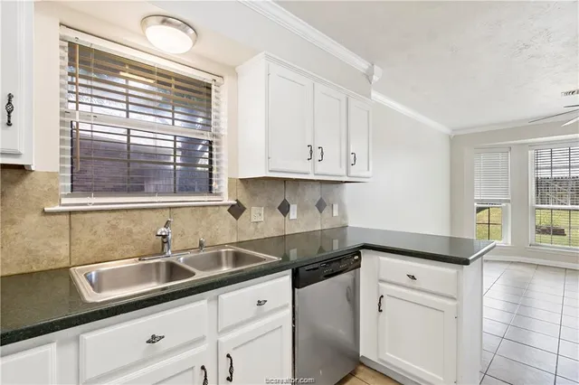 a kitchen with granite countertop white cabinets and a window