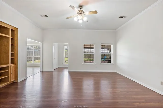 a view of an empty room with a window and wooden floor