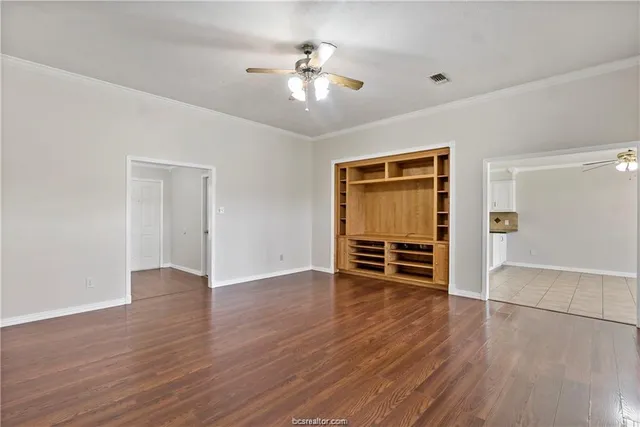 an empty room with wooden floor closet and windows