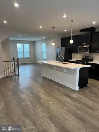 a view of kitchen with kitchen island a sink dishwasher a stove and a refrigerator with wooden floor