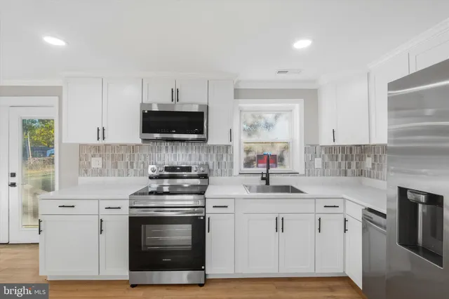a kitchen with white cabinets and appliances