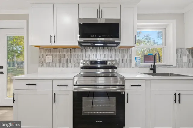 a kitchen with stainless steel appliances a stove and a white cabinets