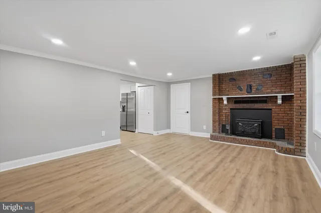 an empty room with wooden floor fireplace and window