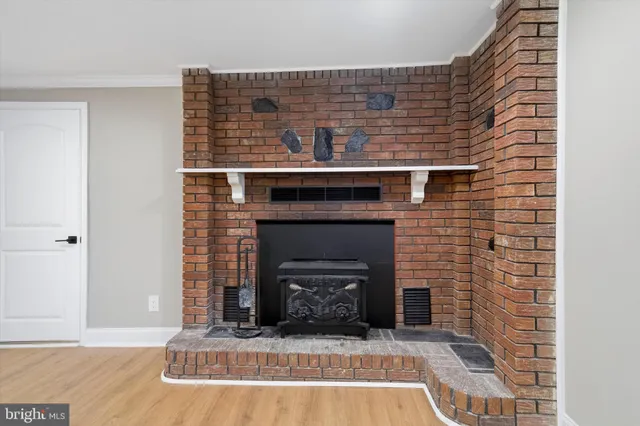 a view of an empty room with wooden floor and a fireplace