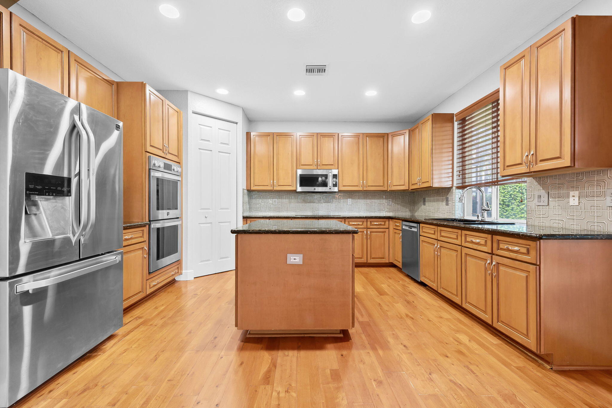 10774 Sunset Ridge Circle Boynton Beach, FL 33473 - Photo 8 of 39 a kitchen with stainless steel appliances granite countertop a refrigerator a sink dishwasher a stove and white countertops with wooden floor