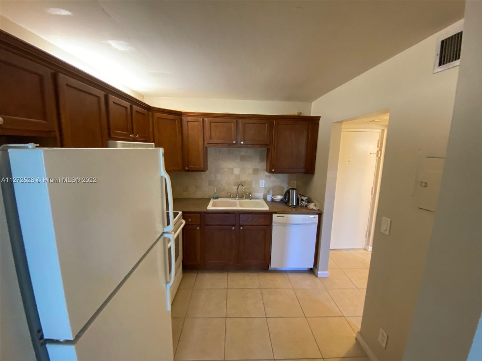 9355 Southwest 8th Street, Unit 216 Boca Raton, FL 33428 - Photo 12 of 15 a kitchen with a refrigerator sink stove and cabinets