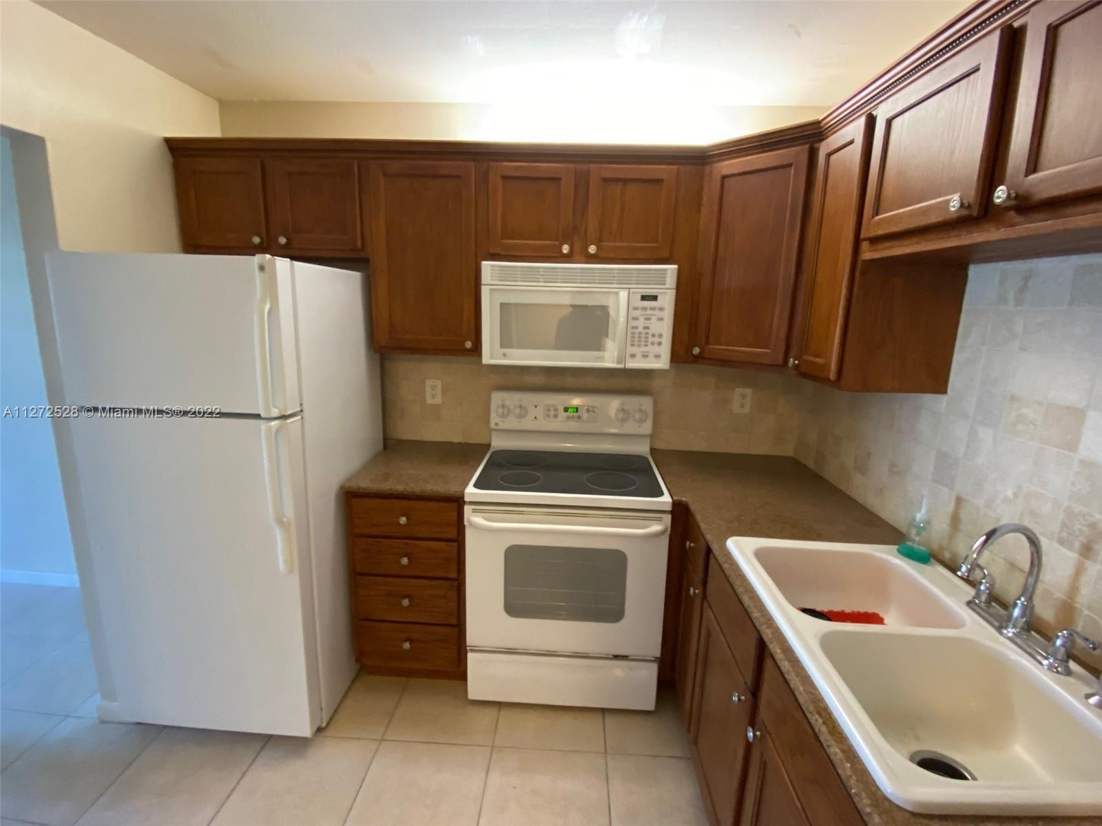 9355 Southwest 8th Street, Unit 216 Boca Raton, FL 33428 - Photo 3 of 15 a kitchen with a refrigerator sink stove and cabinets