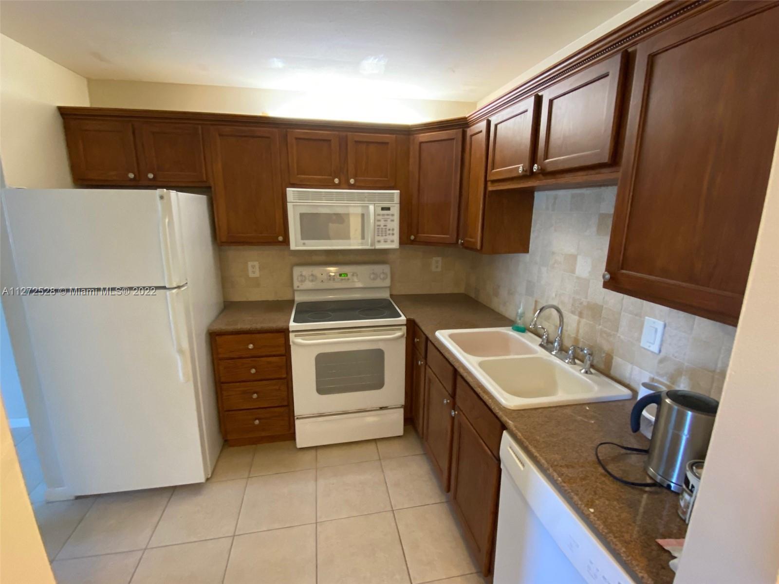 9355 Southwest 8th Street, Unit 216 Boca Raton, FL 33428 - Photo 4 of 15 a kitchen with a stove sink and refrigerator