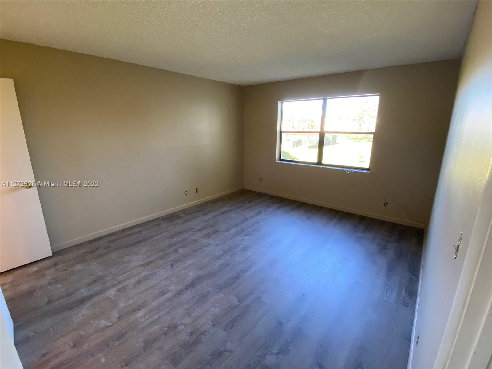 9355 Southwest 8th Street, Unit 216 Boca Raton, FL 33428 - Photo 7 of 15 an empty room with wooden floor and windows