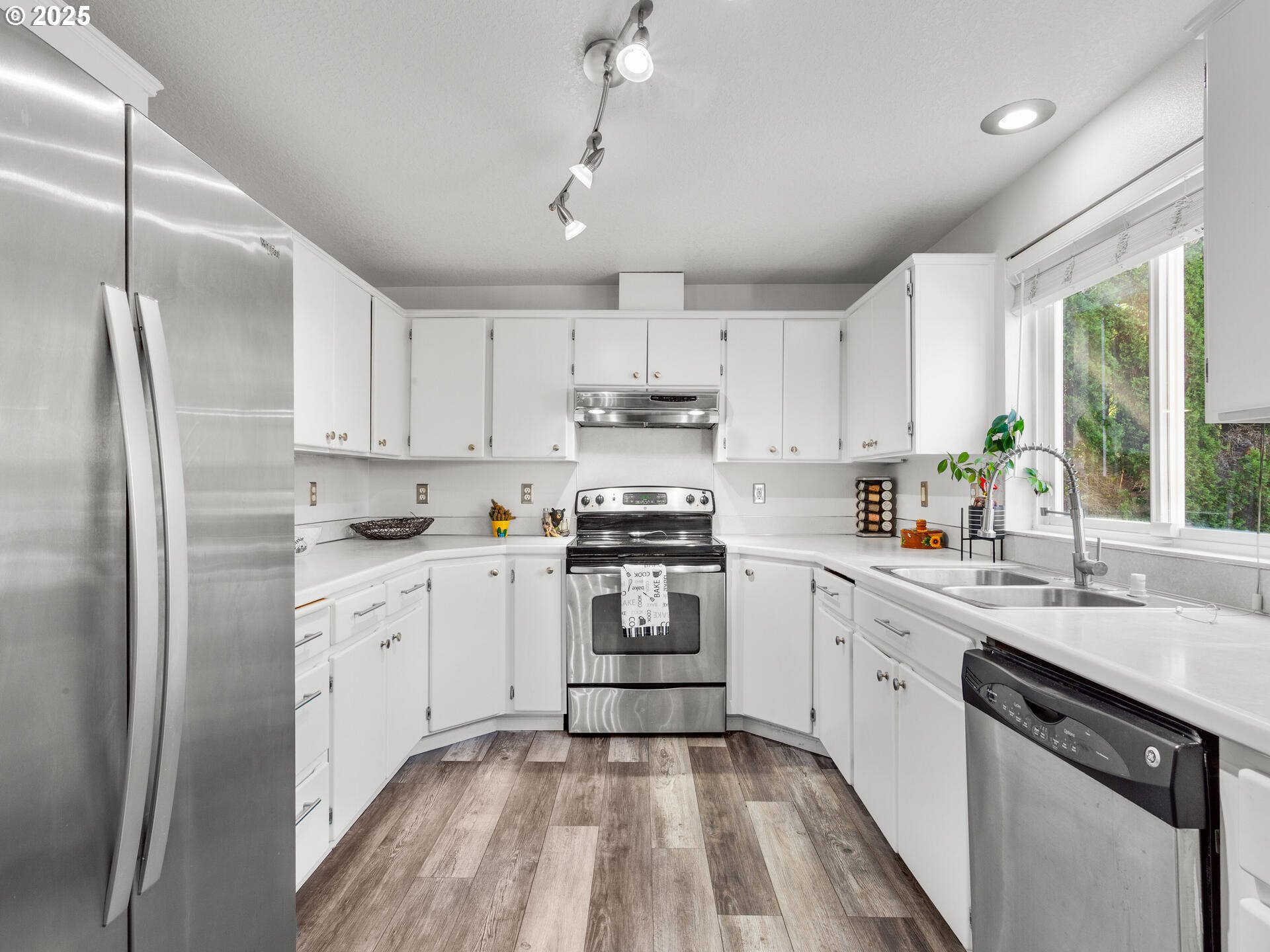 8292 Northeast Snowberry Loop Vancouver, WA 98664 - Photo 21 of 48 a kitchen with stainless steel appliances granite countertop a stove a sink dishwasher a refrigerator and white cabinets with wooden floor