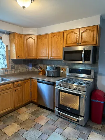 a kitchen with stainless steel appliances granite countertop a stove a sink dishwasher and a refrigerator