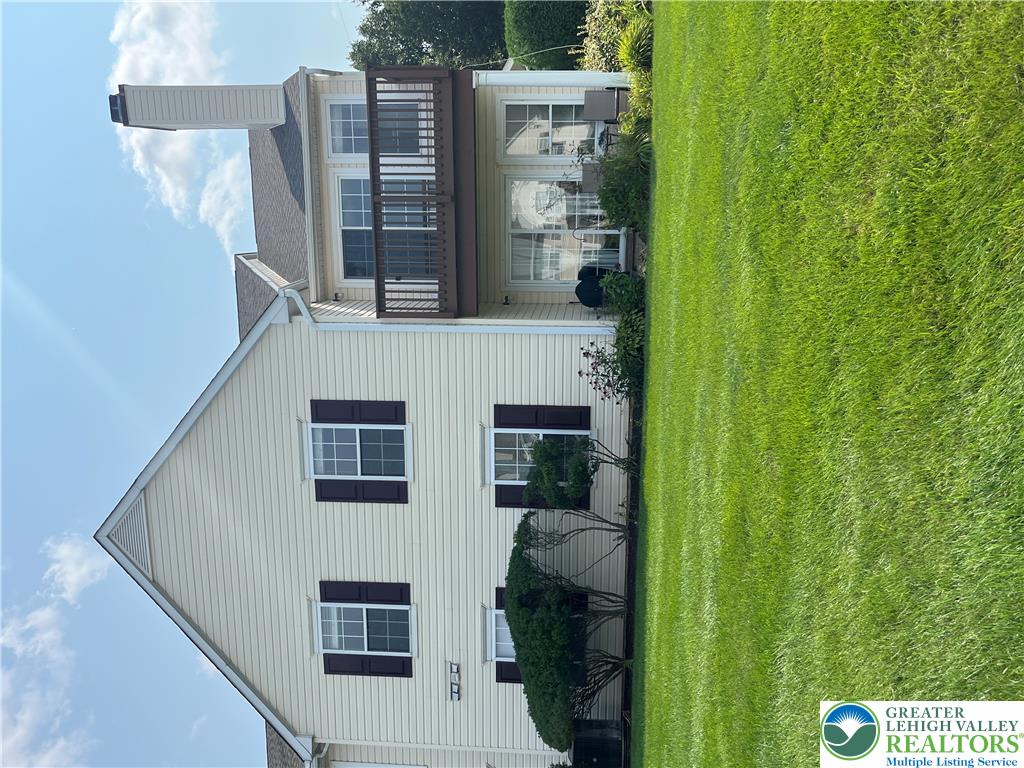 Lush green grass borders this classic multi-level exterior featuring a private upper-level balcony.