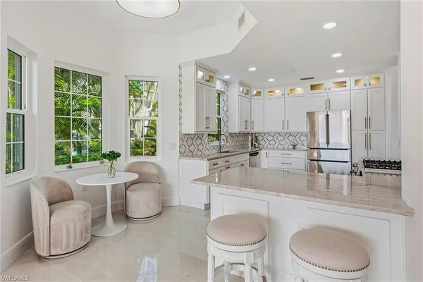 a living room with furniture a large window and kitchen view