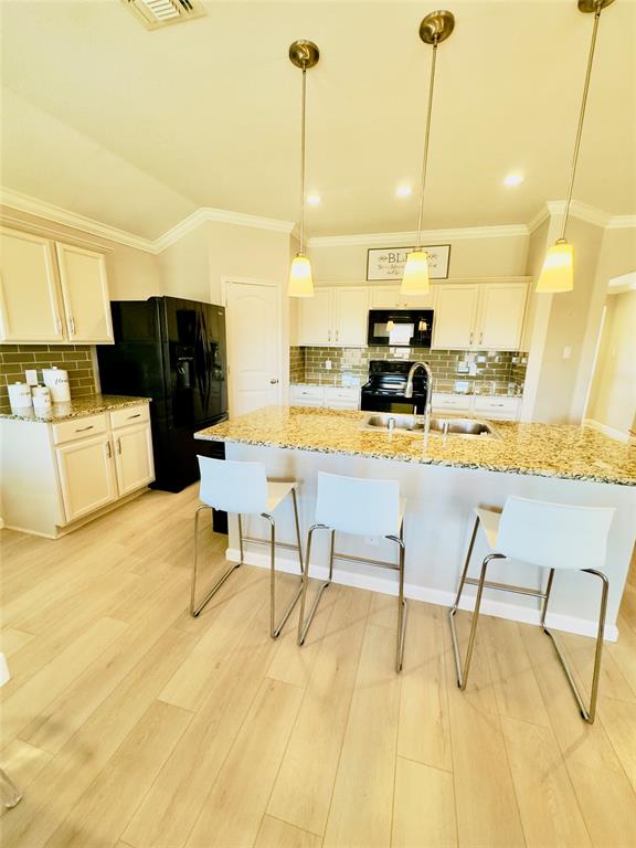 1508 Wild Rye Circle Princeton, TX 75407 - Photo 7 of 17 Kitchen with crown molding, backsplash, light stone countertops, a kitchen bar, and black appliances
