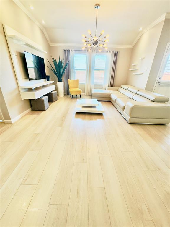 1508 Wild Rye Circle Princeton, TX 75407 - Photo 9 of 17 Living area with a chandelier, ornamental molding, light wood finished floors, and healthy amount of natural light