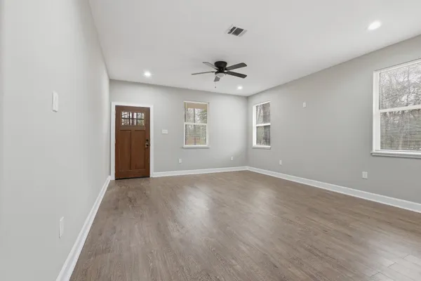 a view of an empty room with a window and wooden floor