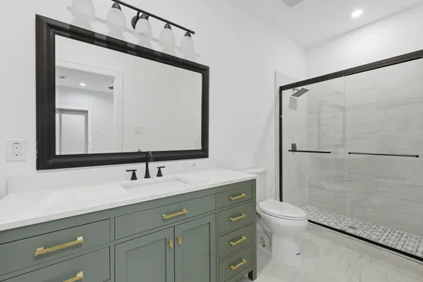 a bathroom with a sink a toilet a mirror and shower