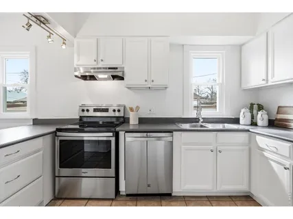 a kitchen with stainless steel appliances granite countertop a dining table chairs and a refrigerator