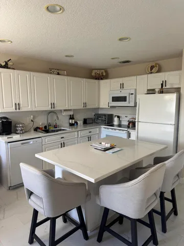 a kitchen with stainless steel appliances granite countertop a stove a sink a table and chairs