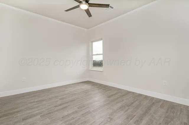 an empty room with wooden floor fan and windows
