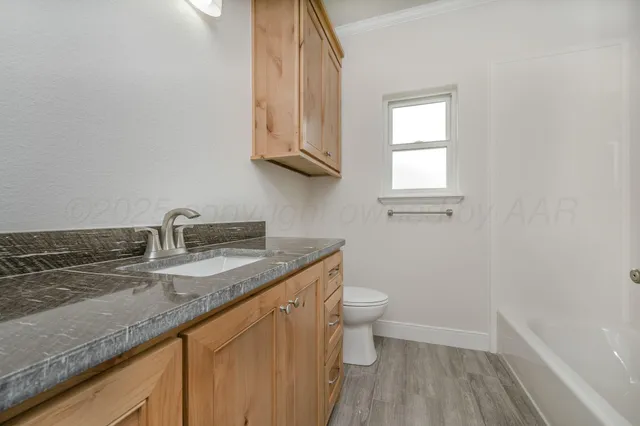 a bathroom with a granite countertop sink a toilet and a window