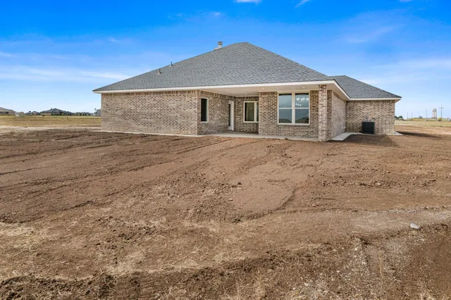 a front view of a house with a dirt yard and mountain view